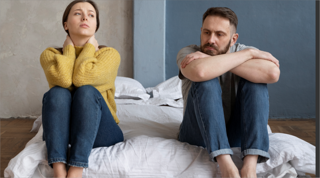Casal sentado afastado em uma cama, demonstrando tristeza e preocupação, representando o impacto da dependência química na família e a importância de buscar ajuda especializada.