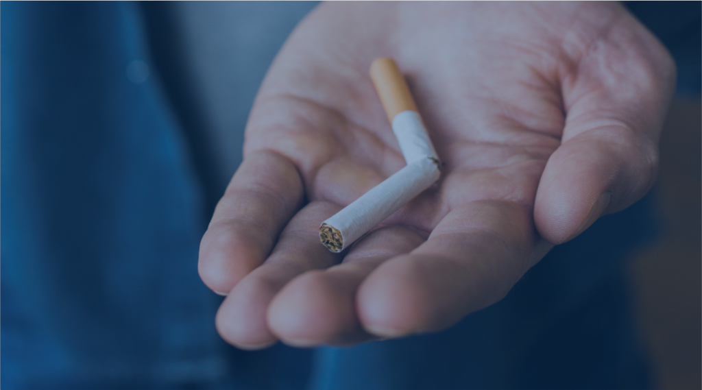 Mão segurando cigarro apagado, representando o Dia Mundial Sem Tabaco e a importância de levar toda dependência a sério.